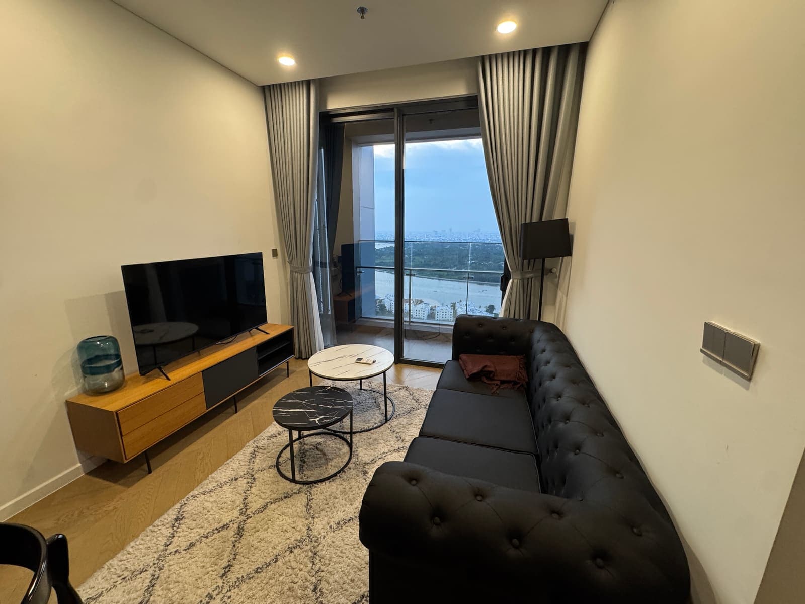 Living room with sofa, TV, and floor-to-ceiling river view